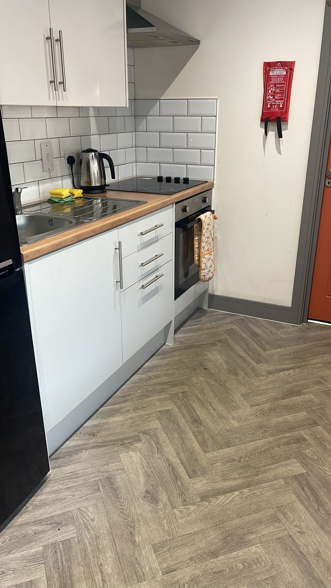 Clean kitchen with white cabinets and herringbone flooring in Derby